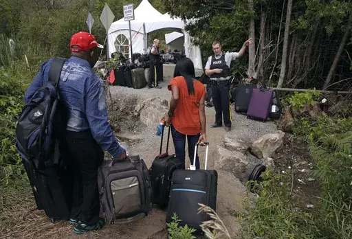A Royal Canadian Mounted Police officer informs a migrant couple of the location of a legal border station, shortly before they illegally crossed from Champlain, N.Y., to Saint-Bernard-de-Lacolle, Quebec, using Roxham Road. Canada’s government is reimposing some visa requirements on Mexican nationals visiting Canada, an official familiar with the matter told The Associated Press on Wednesday, Feb. 28, 2024. Quebec’s premier has been urging the federal government to slow the influx of refugee