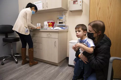 Ilana Diener holds her son, Hudson, 3, during an appointment for a Moderna COVID-19 vaccine trial in Commack, N.Y. on Nov. 30, 2021. On Thursday, April 28, 2022, Moderna asked U.S. regulators to authorize low doses of its COVID-19 vaccine for children younger than 6, a long-awaited move toward potentially opening shots for millions of tots by summer. (AP Photo/Emma H. Tobin, File)
